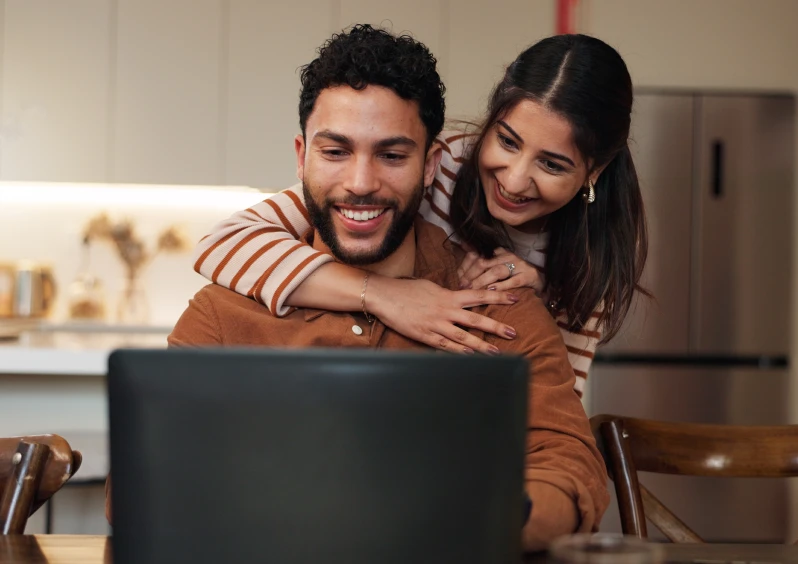 Couple smiling while looking at laptop